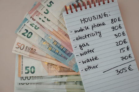 A notebook page with a list of housing expenses and euro banknotes.