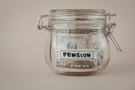 A glass jar with a metal clasp containing banknotes labeled as pension savings.の写真素材