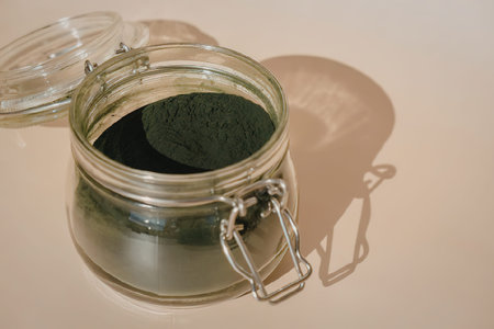 A glass jar with a dark green substance inside, the lid is partially removed.の写真素材