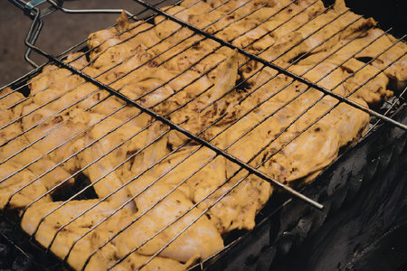 A close-up view of grilled chicken pieces on a barbecue grill.