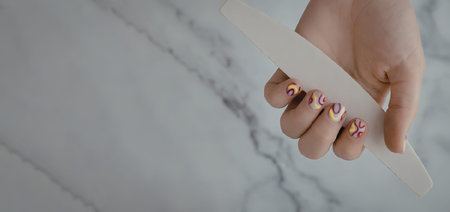 a hand holding a nail file with a marble background