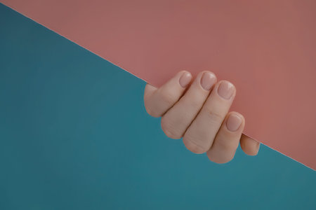 A hand holding a piece of paper with a blue and red background
