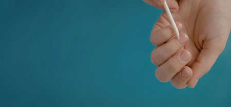 A hand holding a swab against a blue background