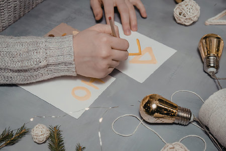 A person's hands are shown decorating an ornament on a table with various craft supplies.