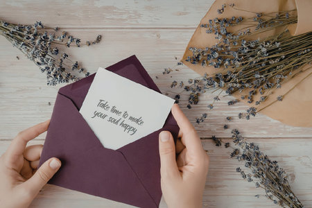 Hands holding a purple envelope with a white card.