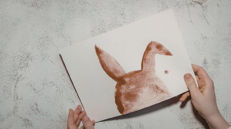 A pair of hands holding a white piece of paper with a brown duck drawing on it.の写真素材