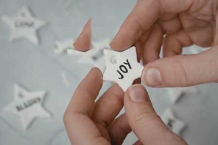A person's hands are holding a star shaped paper with the word 'joy' written on it. The background...