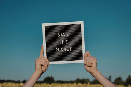 A person holding a sign that reads 'Save The Planet' with a natural backgroundの写真素材
