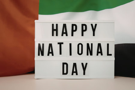 A light box with 'HAPPY NATIONAL DAY' in front of a flagの写真素材