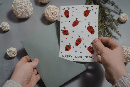 A person holding a new year card with a green envelope, surrounded by festive decorations.の写真素材