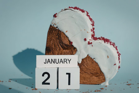 A heart shaped cake with white icing and red sprinkles next to a calendar showing January 21の写真素材