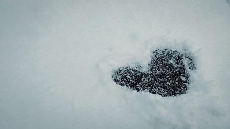 A heart shape formed in the snow, likely made by footprints or a natural formation.の写真素材