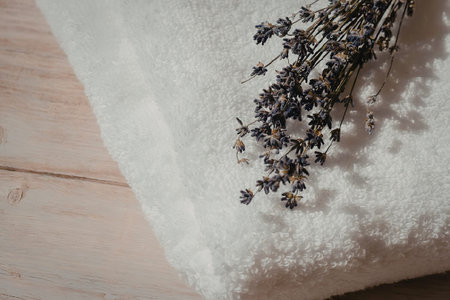 A bunch of lavender flowers on a white towel, placed on a wooden surface.の写真素材