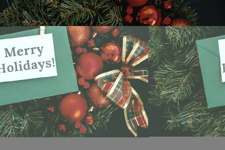 A festive holiday wreath adorned with red ornaments, berries, and a green card with a 'Merry...