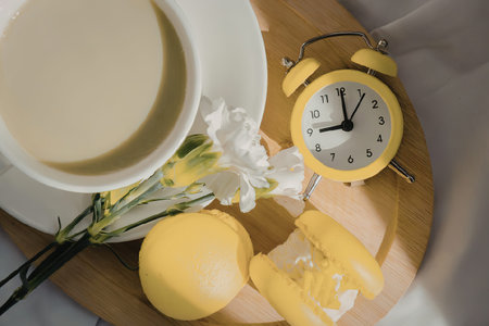 An image of a cup of tea with an alarm clock on a wooden board
