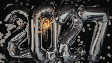 The image shows silver balloons in the shape of the year 2027 with confetti and a sparkler.の写真素材