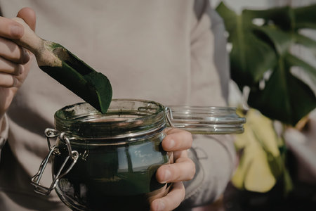 A person is holding a glass jar filled with green paint and a paintbrush.の写真素材