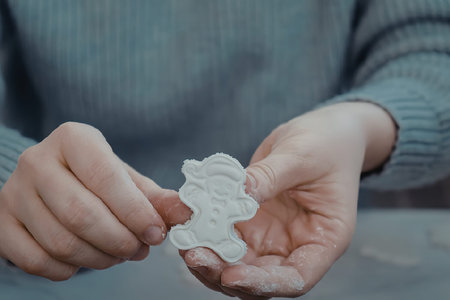 A person in a blue sweater holding a white cookie cutter.の写真素材