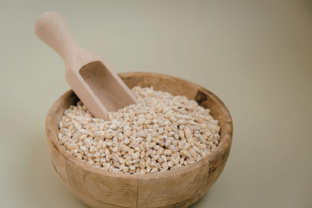 A wooden bowl filled with sesame seeds and a small wooden scoop.の写真素材
