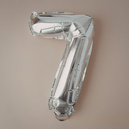 A shiny silver number seven balloon against a beige background