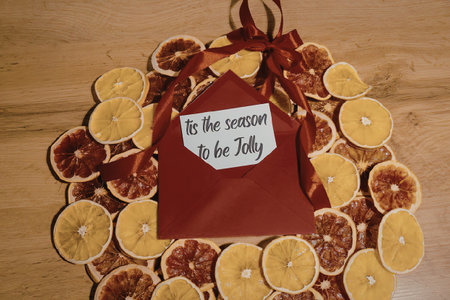 A creative arrangement of dried orange slices forming a circle around a red fabric shape with a...