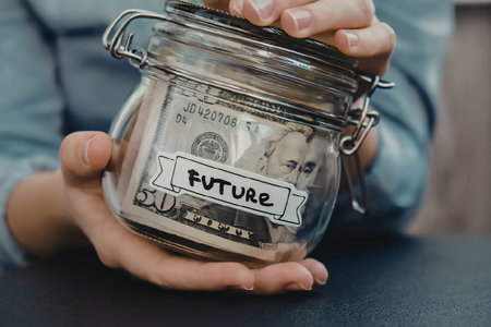 A person holding a glass jar labeled 'FUTURE' filled with dollar bills, representing saving for the...