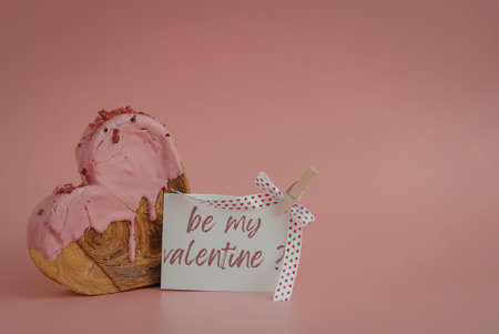 A delicious-looking donut with pink frosting and a Valentine's Day card