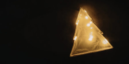 A triangle shaped Christmas light decoration against a dark background