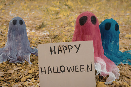 Three ghost costumes in purple, pink, and blue with a Happy Halloween signの写真素材