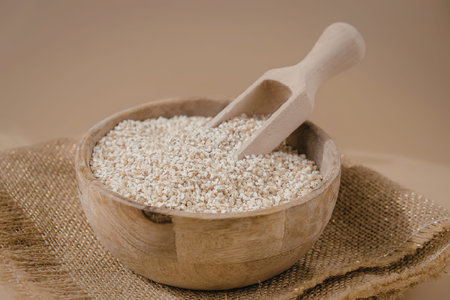 A wooden bowl filled with oats and a wooden scoop on a burlap cloth