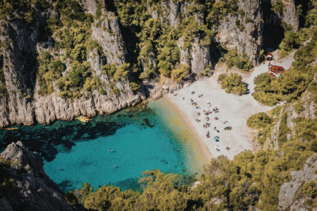 An aerial view of a secluded beach with clear turquoise water, surrounded by rocky cliffs and lush...