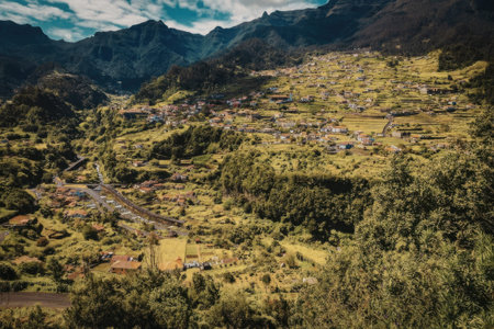 A scenic view of a mountainous landscape with lush greenery and a small village nestled in the valley.の写真素材