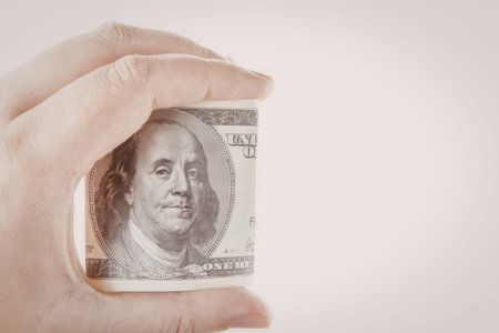 A hand is holding a dollar bill with the portrait visible.