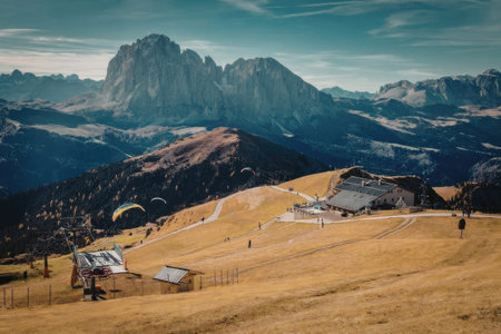 a paraglider flies over a mountainous landscape with a large mountain in the background and a small...