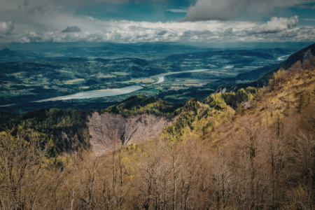 A scenic view of a mountainous landscape with a lake in the distance. The foreground features dry...