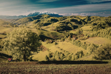 A serene landscape of rolling hills and mountains covered in lush greenery under a cloudy sky.の写真素材