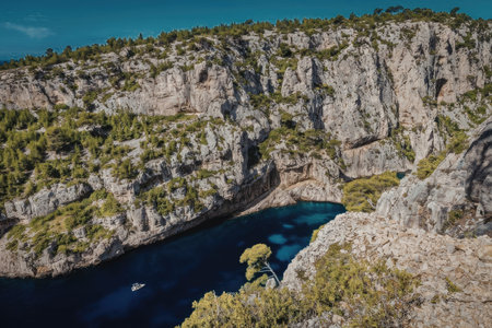 A stunning aerial view of a rocky cliffside with a serene blue body of water and lush greenery