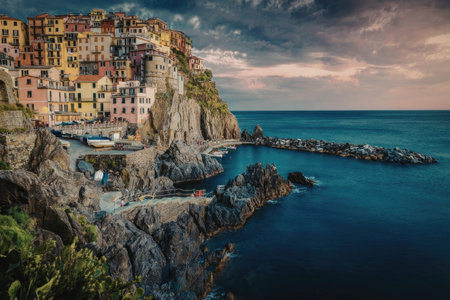 A picturesque cliffside town with colorful houses overlooking the ocean at sunset.