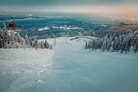 A serene winter landscape featuring a snow-covered mountain slope with ski tracks, surrounded by...