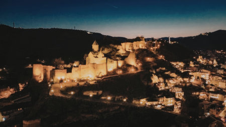 An aerial view of a city lit up at dusk with a mountain range in the background