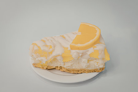 A slice of cheesecake with a layer of orange topping and a slice of orange on top, served on a white plate.の写真素材