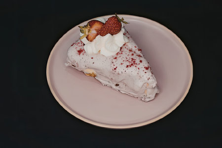 A slice of cake with white frosting, strawberries, and red sprinkles on a pink plate.