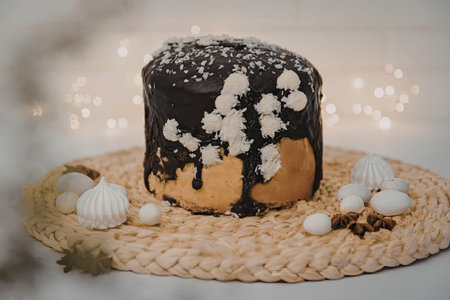 A small chocolate cake with white decorations on a woven mat