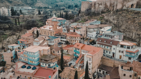 Aerial view of a colorful town with buildings on a hillside, featuring terracotta roofs and vibrant...