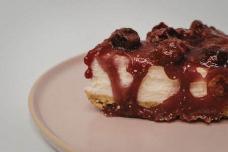 A slice of cheesecake with a rich berry topping on a pink plate