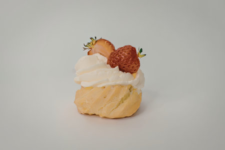 A single cream puff topped with white cream and two fresh strawberries on a plain background