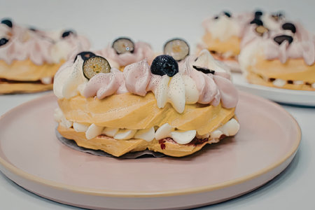 A close-up shot of a waffle sandwich with pink frosting, fresh fruit, and nuts on top, served on a...
