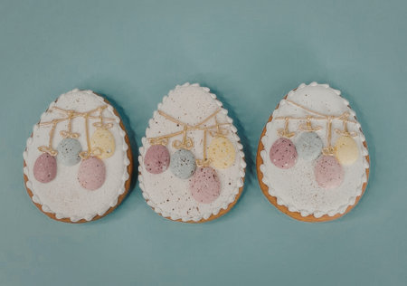 Three decorated Easter egg-shaped cookies with white icing and colorful eggs