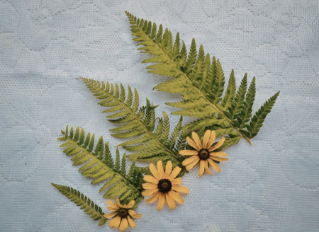 A delicate arrangement of green fern leaves and vibrant yellow flowers on a light gray background