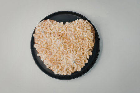 A heart shaped serving of pasta on a black plate against a plain background.の写真素材